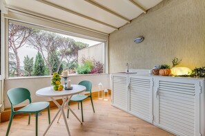 Una piccola cucina open space con zona pranzo e vista su alberi e giardino.
