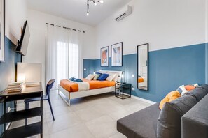 Um quarto moderno com cama, mesa de cabeceira, luminária e escrivaninha com livros.