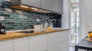 A modern kitchen with a wooden countertop, white cabinets, and a backsplash of dark tiles.