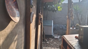 Un pasillo estrecho con suelo de baldosas, una puerta de madera y un pequeño electrodoméstico al fondo.