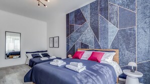 Een moderne hotelkamer met een groot bed, twee nachtkastjes, een spiegel en een wand met een geometrisch patroon.