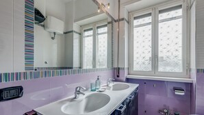 Een badkamer met twee wasbakken, een grote spiegel en een raam.