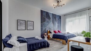 Een moderne slaapkamer met twee bedden, een bureau en een groot abstract kunstwerk aan de muur.