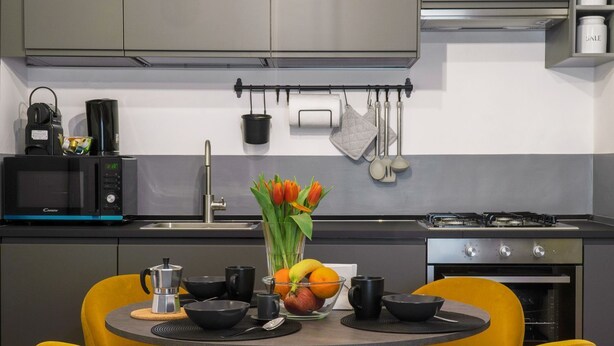 Een moderne keuken met een eethoek, voorzien van een magnetron, fornuis, spoelbak en een tafel met stoelen.