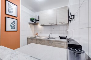 Een moderne keuken met witte kastjes, een roestvrijstalen spoelbak en een marmeren aanrecht.