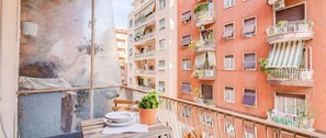 A balcony with a table, chairs, and potted plants.
