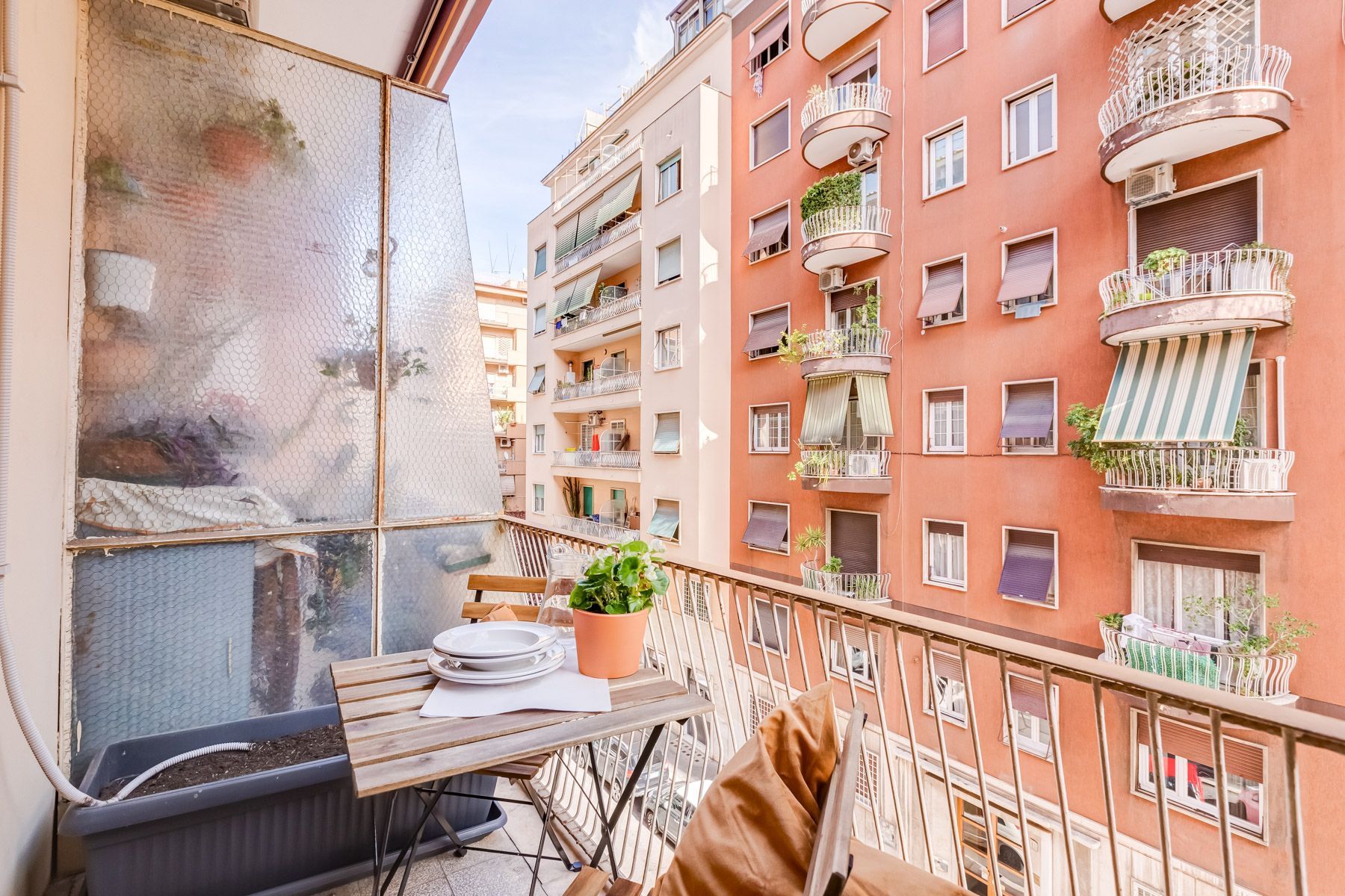 Un balcone con tavolo, sedie e piante in vaso.