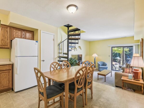 A compact kitchen with a dining area, a spiral staircase, and a view of the outdoors.