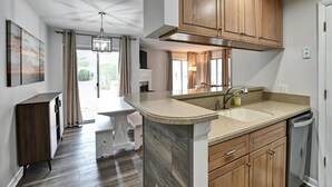 Una cocina moderna con armarios de madera, encimera de granito y lavavajillas empotrado.
