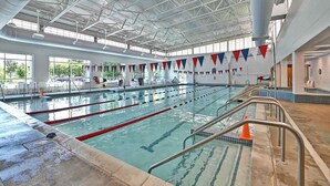 Una piscina interior con varias pistas de natación, un techo alto y vistas al exterior.
