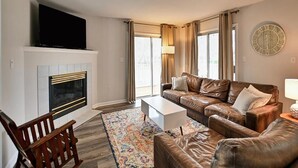 Una sala de estar con chimenea, sofá de cuero y televisor de pantalla plana.