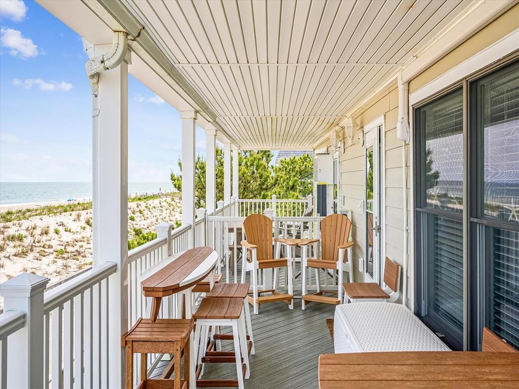 A covered outdoor area with wooden furniture and a view of the beach.