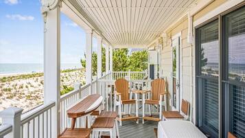 A covered outdoor area with wooden furniture and a view of the beach.