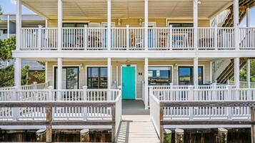 A multi-story building with white railings and a wooden deck.