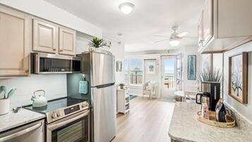 A modern kitchen with stainless steel appliances, a marble countertop, and light wood cabinetry.