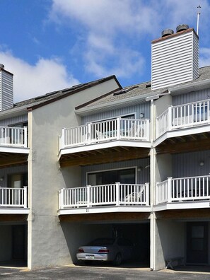 A multi-story residential building with balconies, a garage, and a car parked inside.