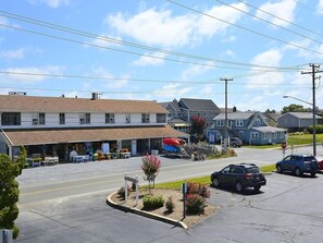 A street view with a motel, outdoor seating area, and parked vehicles.