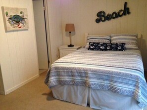 A bedroom with a bed, a nightstand, a lamp, and a wall decoration.