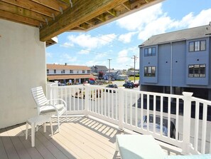 A wooden deck with white railings, a white chair, and a small table.