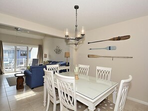 A dining area with a white table and chairs, a chandelier, and a view of the outdoors.
