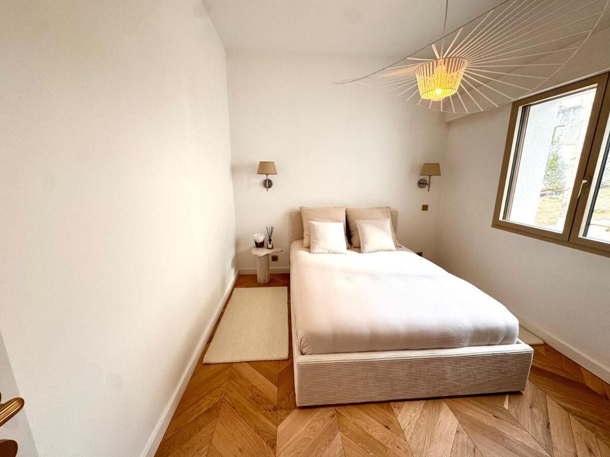 Ein Schlafzimmer mit einem Bett, einem Nachttisch, einer Lampe und einem Fenster.