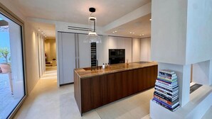 A modern kitchen with a central island, built-in appliances, and a stack of books on a pedestal. - Eclat de Provence - luxury villa - calanques de cassis - (Allauch)
