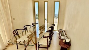 A dining area with a glass-top table and chairs, a small side table with decorative items, and a view through a window. - Eclat de Provence - luxury villa - calanques de cassis - (Allauch)