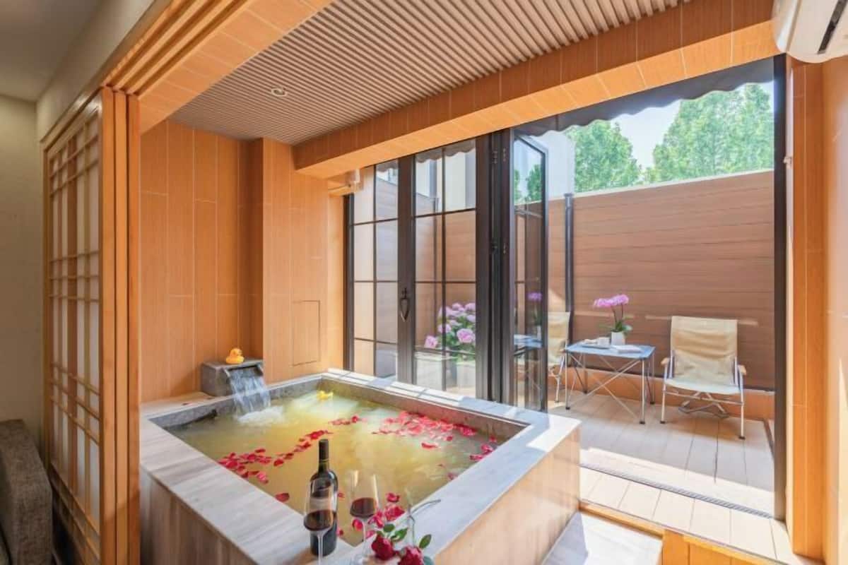Uma área de spa com hidromassagem, pétalas de rosas e uma garrafa de vinho.