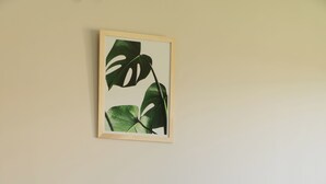 Una cama bien hecha con ropa de cama verde y una planta enmarcada en la pared.