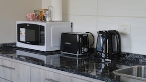 Una cocina con microondas, tostadora y cafetera sobre una encimera de granito.