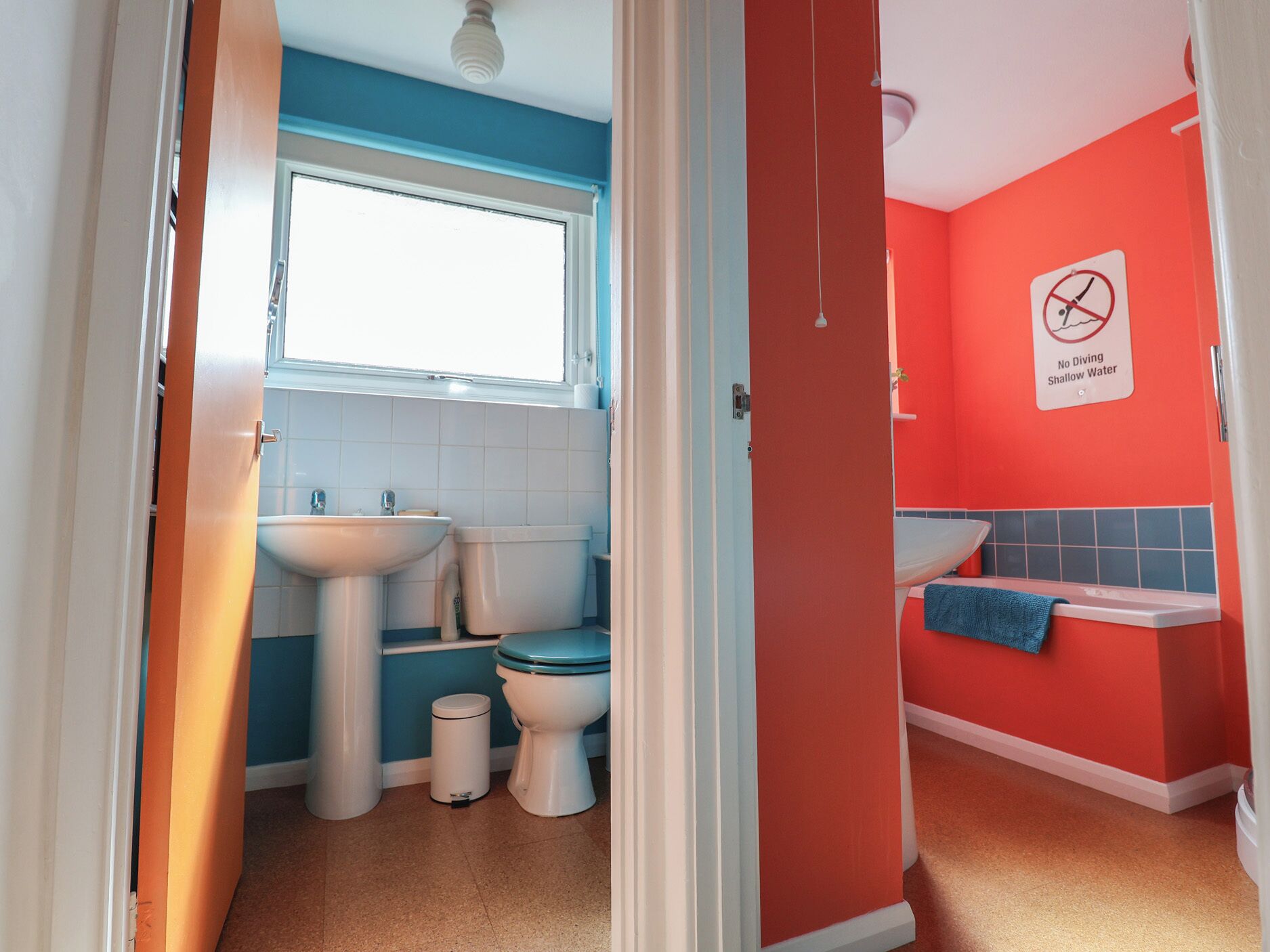 Un baño con una decoración azul y roja, que incluye un lavabo, inodoro y zona de ducha.