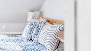 Une chambre à coucher avec un lit, des oreillers, une table de chevet et une lampe.