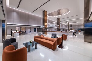 Un vestíbulo moderno con mostrador de recepción, zona de estar y cocina al fondo.