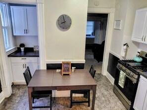 A kitchen with white cabinets, a clock, a welcome sign, and a stove.