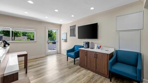 Een moderne wachtruimte met een receptiebalie, een flatscreen televisie, een blauwe bank en een houten kast.