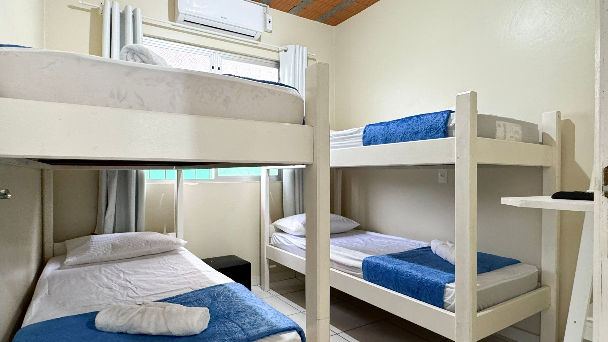 Een slaapkamer met stapelbed, witte beddengoed en blauwe accenten.