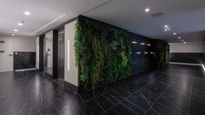 En moderne lobby med et sort marmorgulv, en lodret væg med grøn beplantning og en marmorvæg med geometrisk mønster.