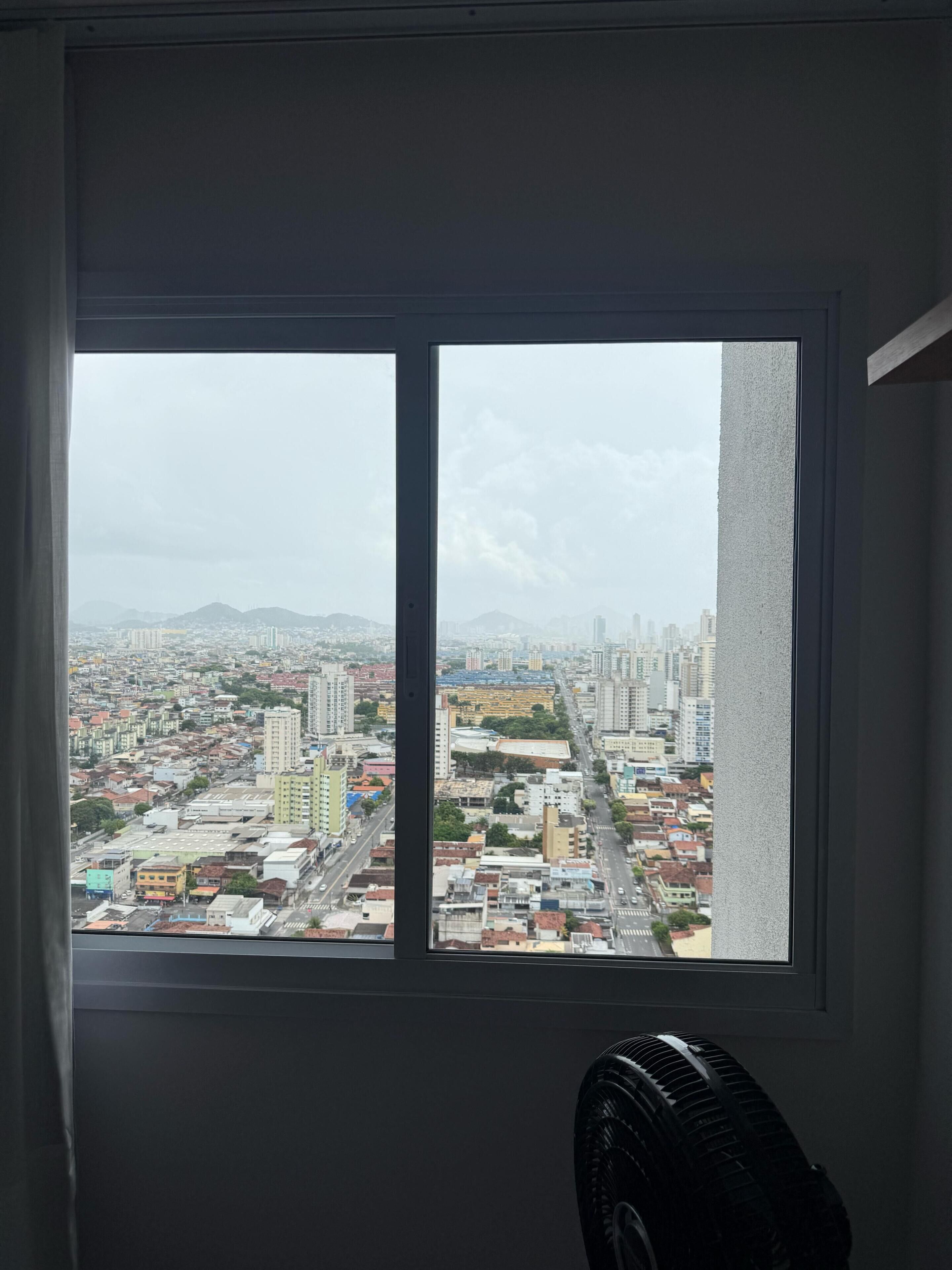 Quarto com uma janela ampla com vista para a paisagem urbana.