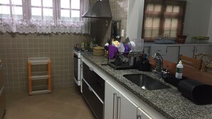 A kitchen with a granite countertop, stainless steel appliances, a sink, and a window with blinds. - 4-bedroom house in delightful Riviera, 15 minute walk to the beach and the mall. (Bertioga)