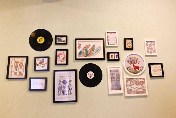 A wall with various framed artworks and vinyl records.