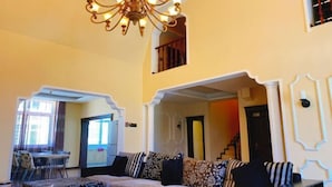 Un salon avec un canapé, un lustre et un escalier menant à l’étage supérieur.