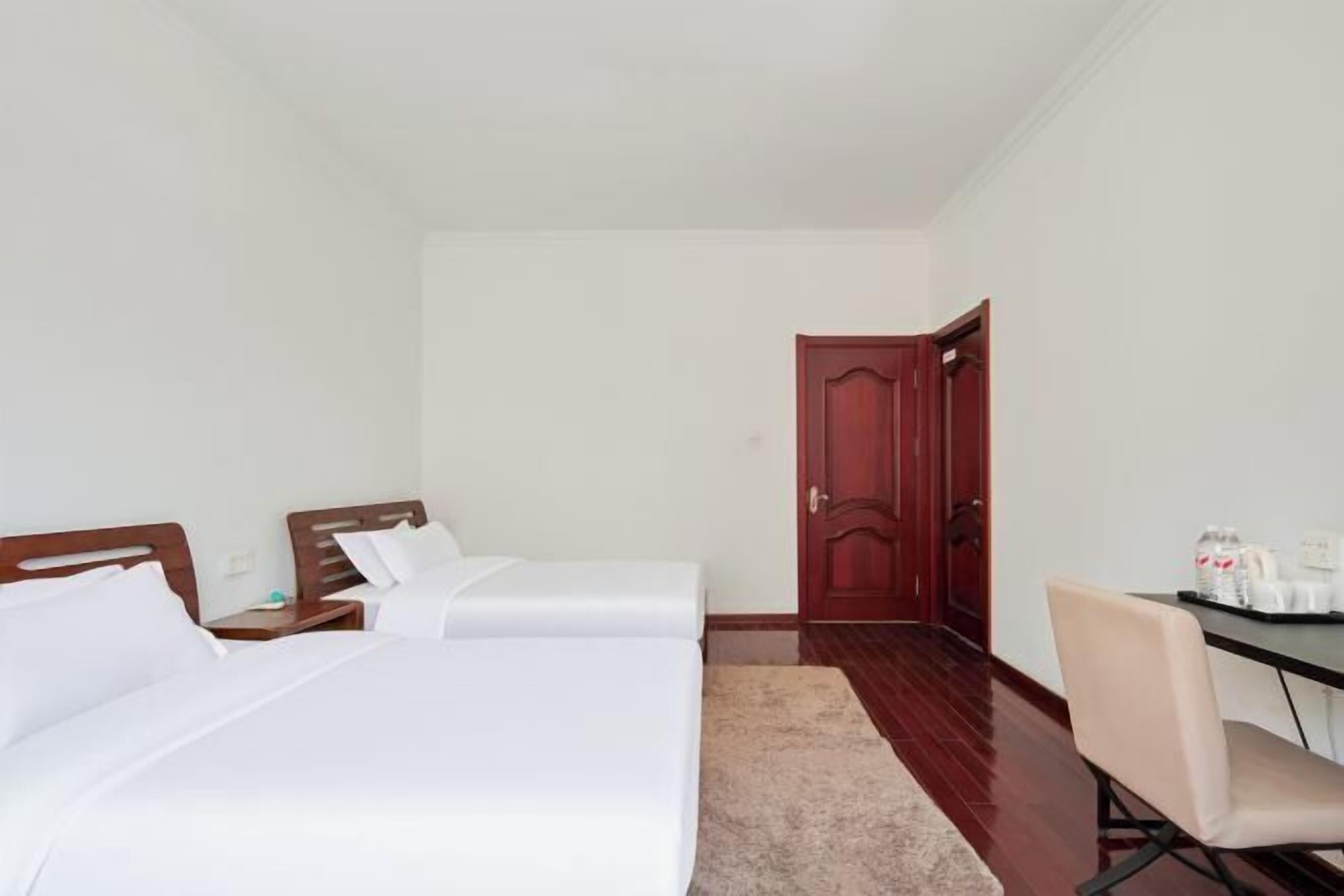 Habitación de hotel con dos camas, un escritorio y una silla.