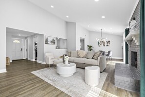 A spacious living room with a modern fireplace, a round coffee table, and a sofa. - Quail Ridge: 3BR House (Charlotte)