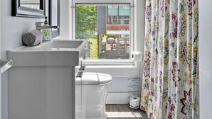 A bathroom with a large window, a toilet, a sink, and a shower curtain. - Historic 2 bedroom central down town location near waterfront - #3 (Halifax)