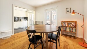Un coin repas avec une table ronde en bois, des chaises noires, une bibliothèque et un lampadaire rouge.