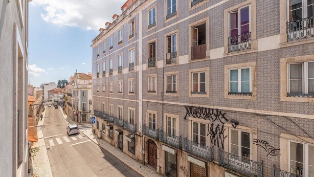 Une rue étroite bordée d’immeubles à plusieurs étages, dont certains sont dotés de balcons et de fenêtres.