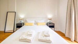 Une chambre d’hôtel avec un grand lit, deux tables de chevet avec des lampes, un miroir et un ensemble de serviettes.