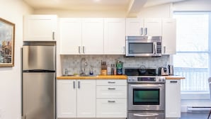 A modern kitchen with stainless steel appliances, white cabinets, and a wooden countertop.