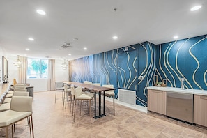 Una habitación de hotel moderna con comedor, cocina y un ventanal que proporciona luz natural.