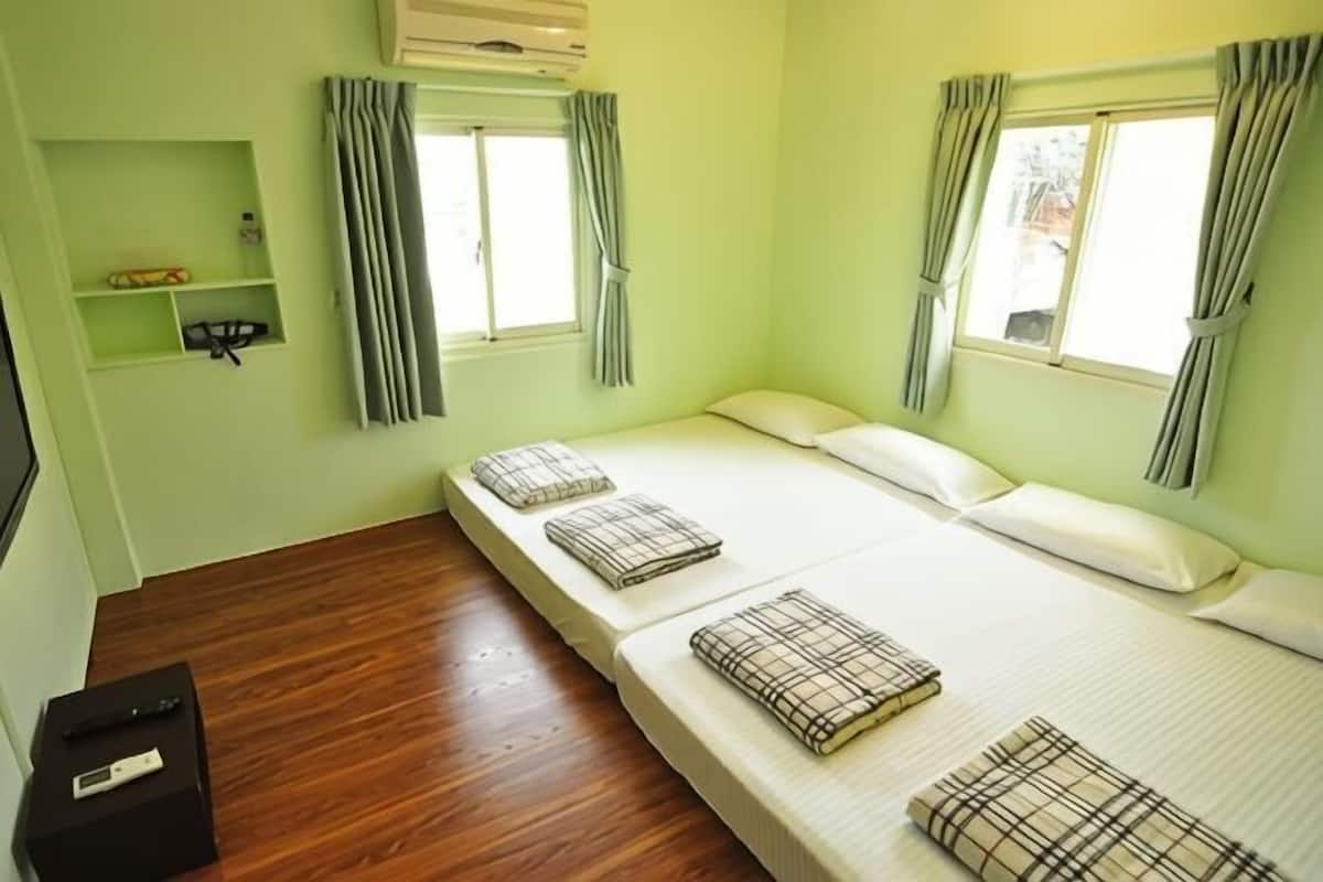 A room with a bed, a small shelf, and a window.
